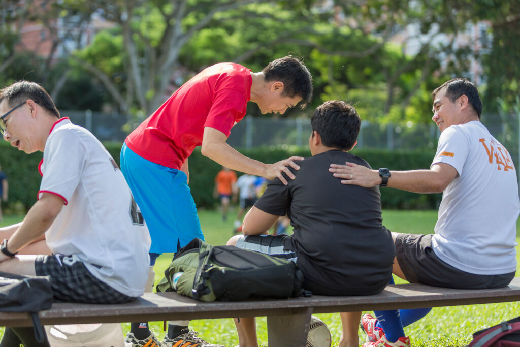 A group of men training to become foster parents sitting on a bench.