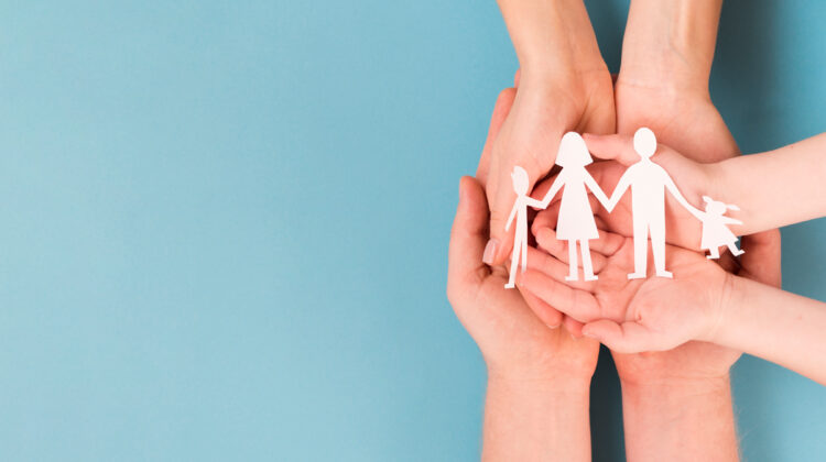 A group of foster parents holding a paper cut out of a family.