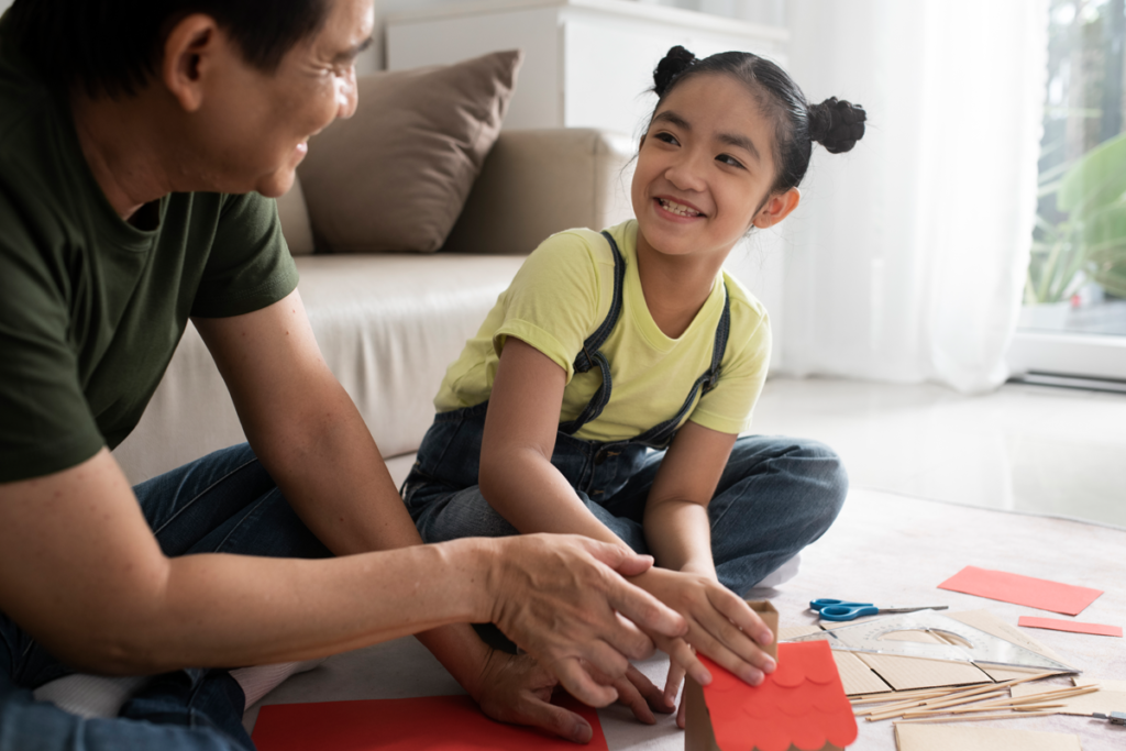 A domestic maid and a little girl learn to make a paper airplane conversing in English at home