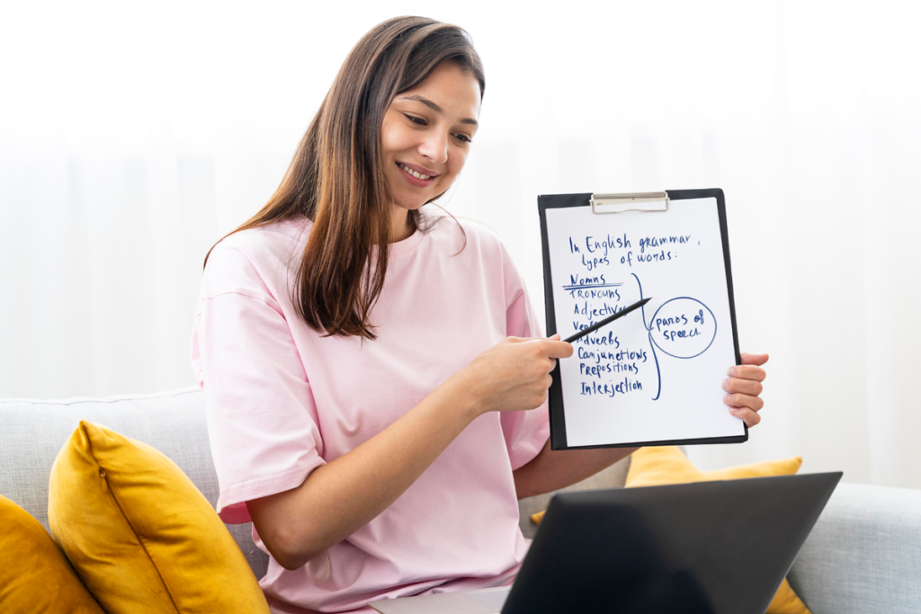 A young woman, who is an English courses instructor for foreign domestic workers, is diligently writing on a clipboard as she sits comfortably on a couch.