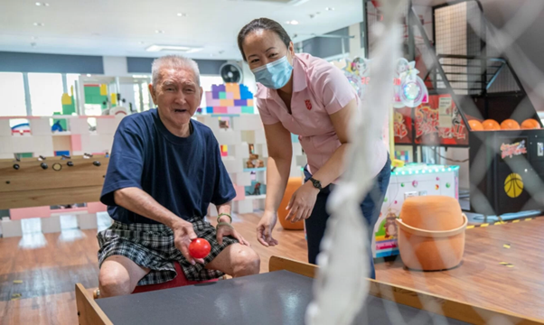 An elderly man with dementia is playing with a ball in a nursing care facility